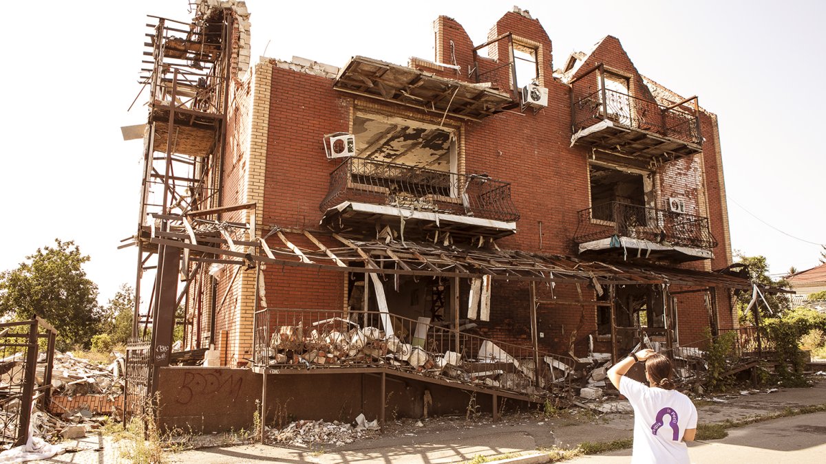 Humanitární pracovnice Človeka v ohrození před zničenou školou na Ukrajině.